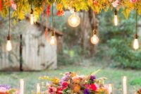 30 a colorful floral wedding installation of red, pink, purple and orange blooms, greenery and bulbs hanging down
