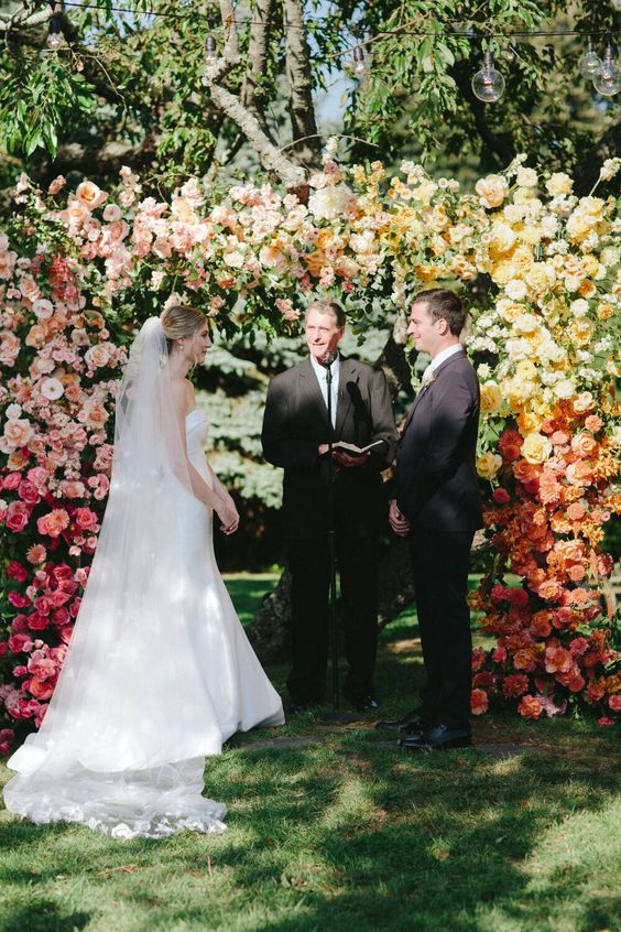 a beautiful ombre wedding arch from pink to blush, yellow and orange is a gorgeous idea for any wedding with plenty of color