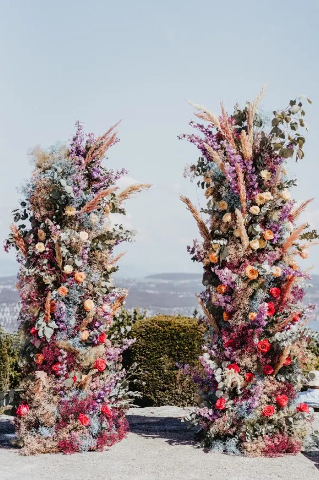 a jaw-dropping colorful wedding altar with blooms of all kinds and colors and pampas grass plus a lovely view