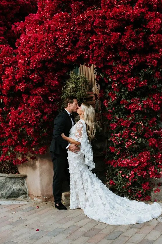 a jaw-dropping wedding arch of living deep red blooms growing here is a fantastic solution for a refined and lush fall wedding