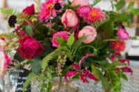 36 a bright and textural wedding centerpiece of light, hot pink and fuchsia blooms and greenery, berries and deep purple blooms for an accent