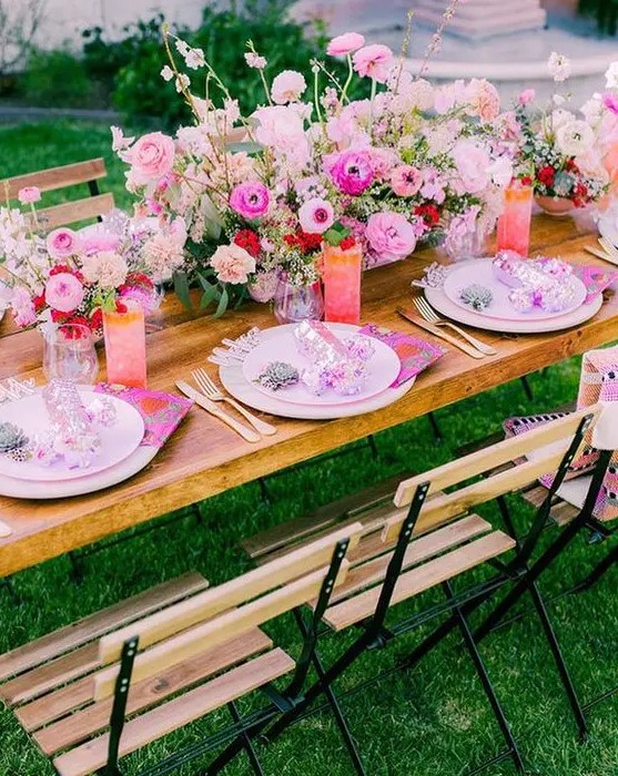 a bright garden wedding tablescape with light pink chargers and plates, a hot pink and red flower centerpiece, hot pink punch and lemonade