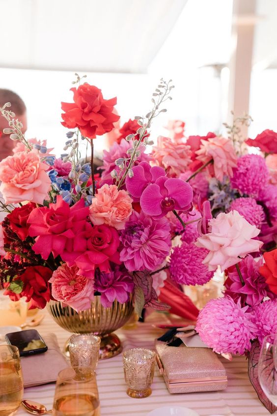 a bright wedding centerpiece of light and hot pink blooms, salmon pink and hot red ones is a lovely idea
