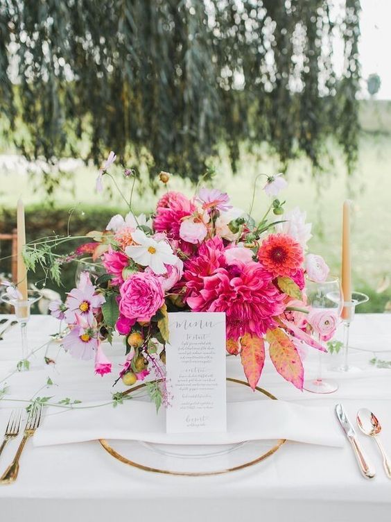 a bright wedding centerpiece of white, light and hot pink and orange blooms, bright foliage and greenery is a bold and cool idea