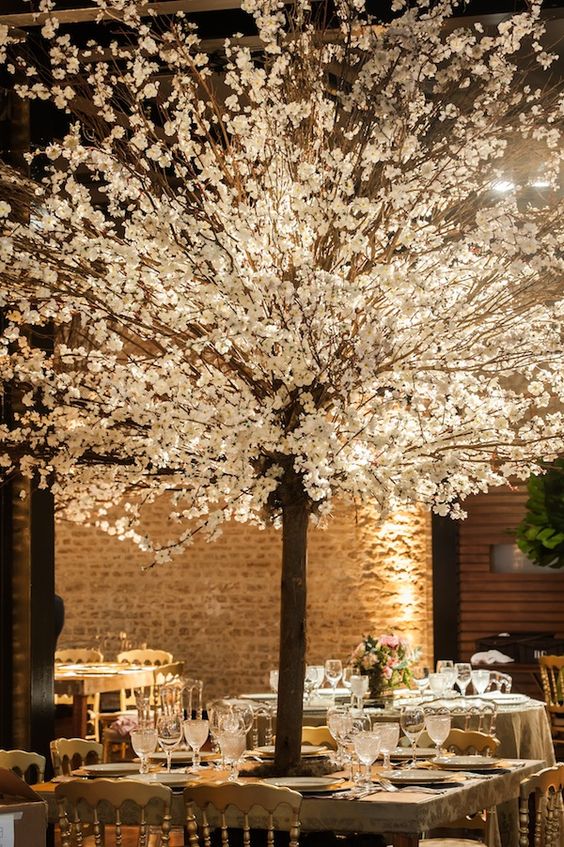 an oversized blooming tree wedding centerpiece created with cherry blossom will easily create an outdoor feel in an indoor space