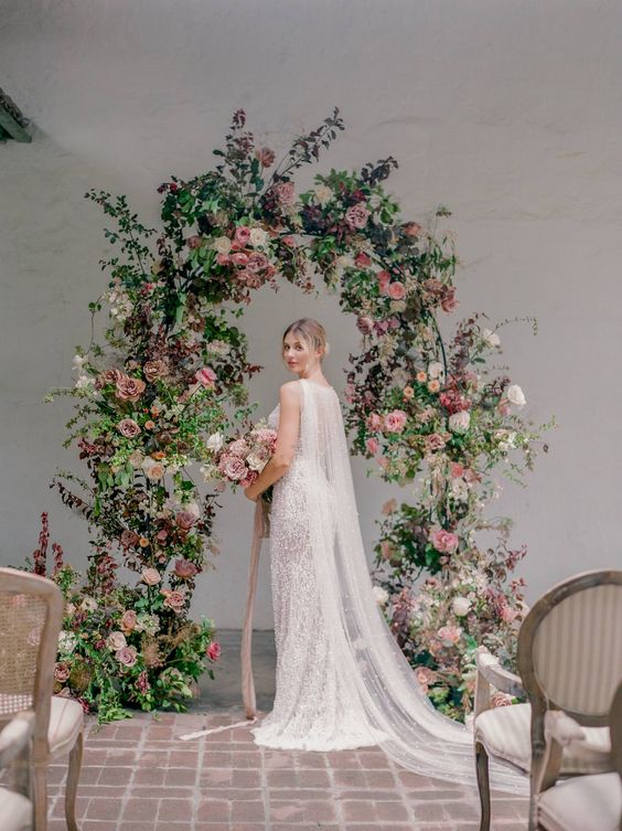 a beautiful and lush wedding arch decorated with greenery, blush, mauve and neutral blooms is a gorgeous solution for a spring or summer wedding