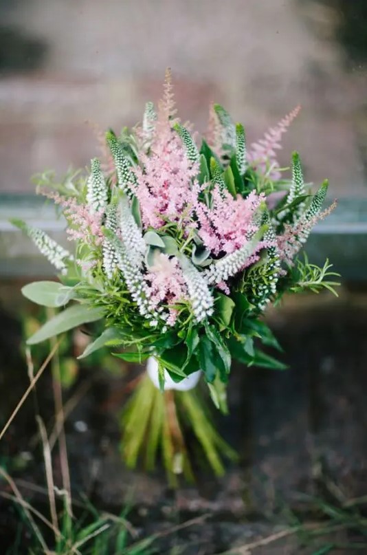 a beautiful small wedding bouquet of pink and white astilbe and greenery with a white ribbon wrap is amazing