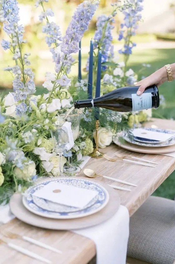 classic wedding table decor done with white and blue delphinium, greenery and blue printed plates is amazing