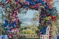 46 a super lush and bold floral wedding arch with blooming branches and flowers of all shades possible and with greenery