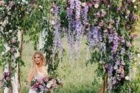 47 a very natural wedding arch with much greenery, purple and light pink blooms and some neutral fabric is wow