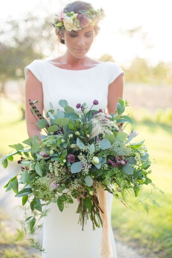 a lush summer wedding bouquet with lots of greenery, small pink blooms and feathers is a bold idea
