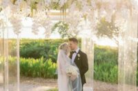 69 a large acrylic wedding arbor covered with lush white orchids and with a view of a field as a backdrop