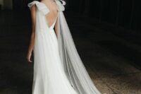 a beautiful bridal look with a plaid mermaid wedding dress with a train, a sheer cape veil with large bows on the shoulders