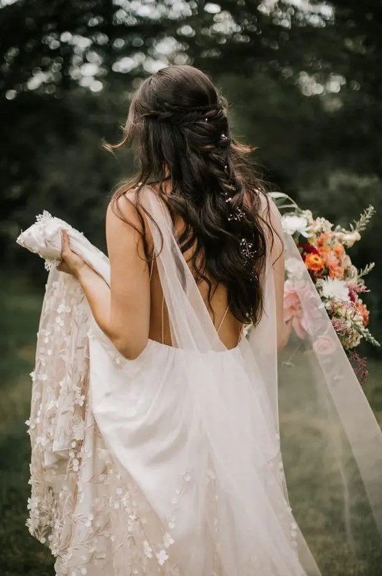 a blush A-line floral embellished wedding dress with an open back and a delicate sheer cape veil to give the bride a more fairy-tale-like look