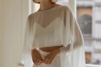 a creative modern bridal look with a crop top, high waisted pants, a sheer high low bridal capelet is wow