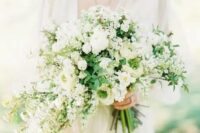 a dimensional white wedding bouquet with a cascading part and greenery for a chic and romantic look