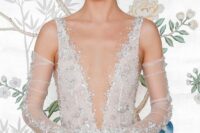 a fantastic A-line wedding dress with a plunging neckline and embellishments and matching tulle gloves are a fab combo for a glam wedding