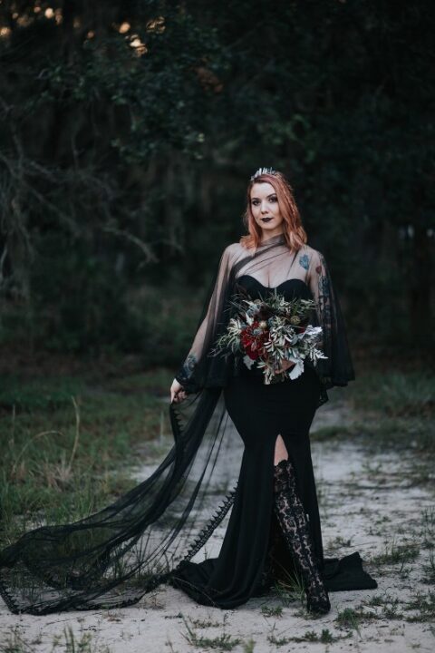 a fantastic strapless black wedding dress with a slit and a sheer black capelet on top plus a crystal crown