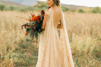 a gold lace wedding dress with an open back and a matching cape veil with a train compose a fantastic look
