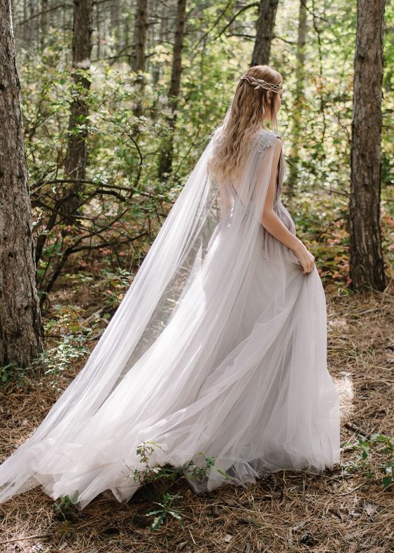 a grey A-line wedding dress with a tulle skirt, a cutout back and a matching sheer capelet with a lace detail on the shoulder