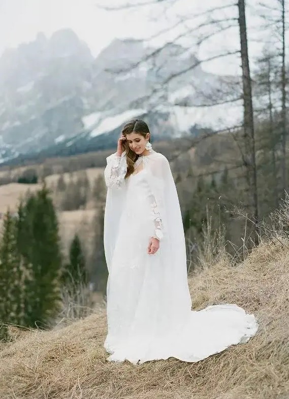 a jaw-dropping refined winter bridal look with an off the shoulder petal wedding dress, a sheer capelet and matching earrings