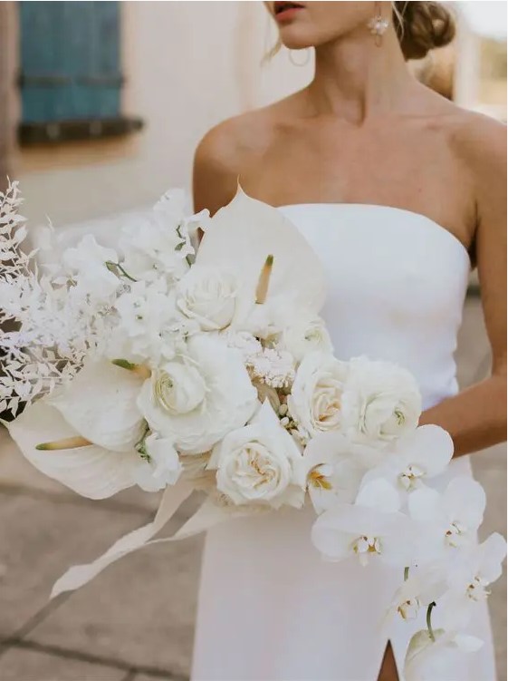 a jaw-dropping white wedding bouquet that includes peony roses, orchids, roses, callas and dried white leaves