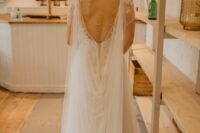 a lace applique wedding dress paired with a tulle cape veil with a train for a sophisticated and chic bridal look