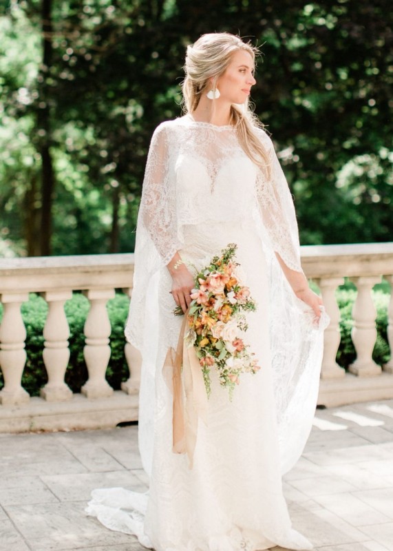 a lace wedding dress plus a matching high low long capelet with a train for a sophisticated and chic look