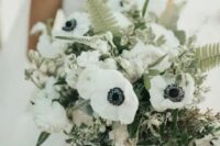 a lovely wedding bouquet of white anemones and peonies, astilbe, greenery and fern leaves looks catchy and wild