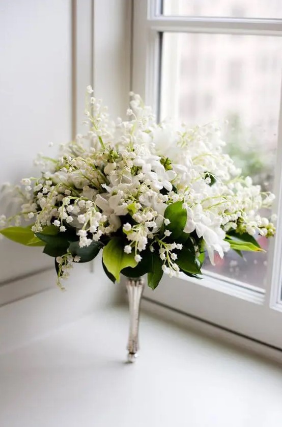 a lush wedding bouquet of lily of the valley, white blooms and foliage and on a silver handle is a beautiful idea for a vintage wedding
