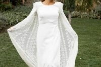 a minimalist plain wedding dress paired with a boho lace capelet with a train compose a trendy bridal outfit