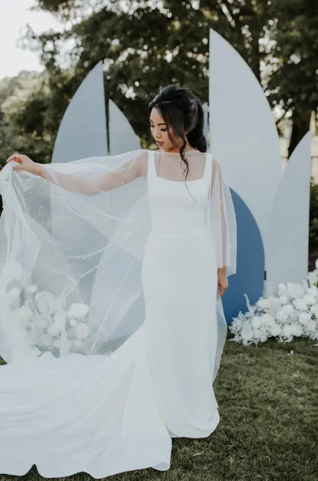 a minimalist sheath wedding dress with thick straps and a pearl capelet that makes the bridal look more girlish and glam