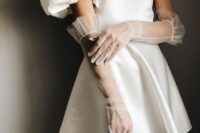 a modern plain wedding dress paired with sheer tulle gloves with ruffles that add girlish chic to the look