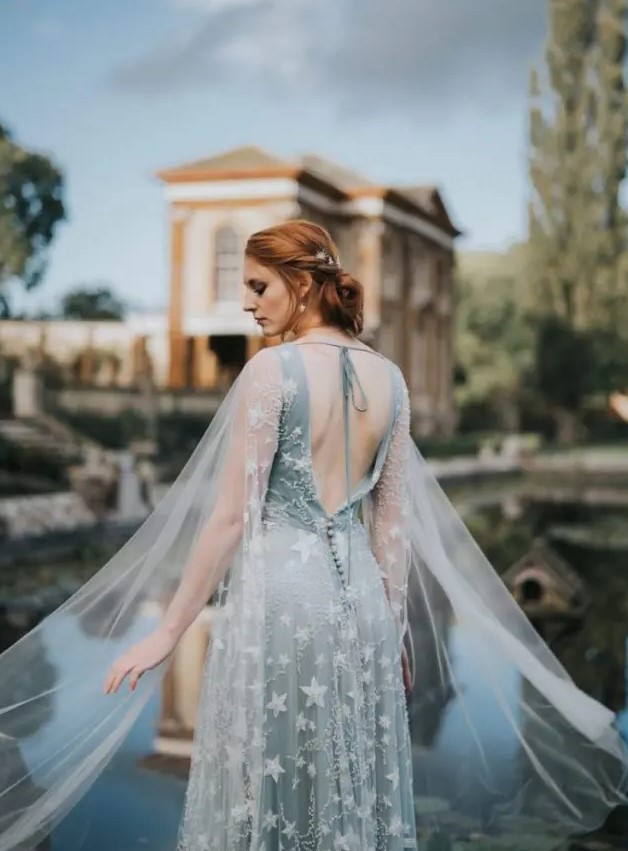 a pale blue star embroidered wedding dress with an open back and a sheer cape veil to make it stand out even more and look dreamier