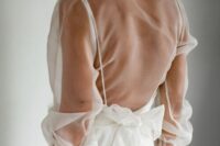 a plain wedding dress with spaghetti straps, an open back and a sheer wrap dress topper with long sleeves are a lovely combo for a modern bride