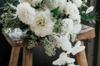 a pretty all-white wedding bouquet of dahlias, orchids, small fillers and greenery looks textural and eye-catchy