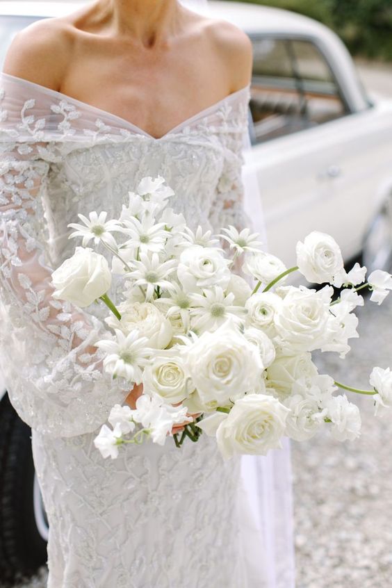 a pretty white wedding bouquet of roses and chamomiles is an unusual idea for a modern bride