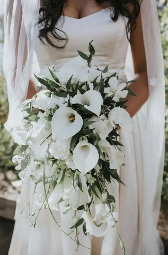 a refined white wedding bouquet with calla lilies and greenery is a chic and sophisticated wedding idea to rock