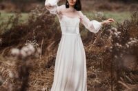 a silk spaghetti strap wedding dress with a pleated skirt and a sheer dress topper are a beautiful combo for a romantic bride