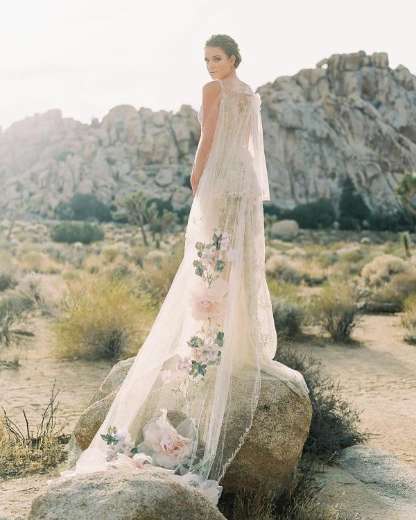 a unique ivory cape veil with oversized floral appliques and a train is a gorgeous statement for your look