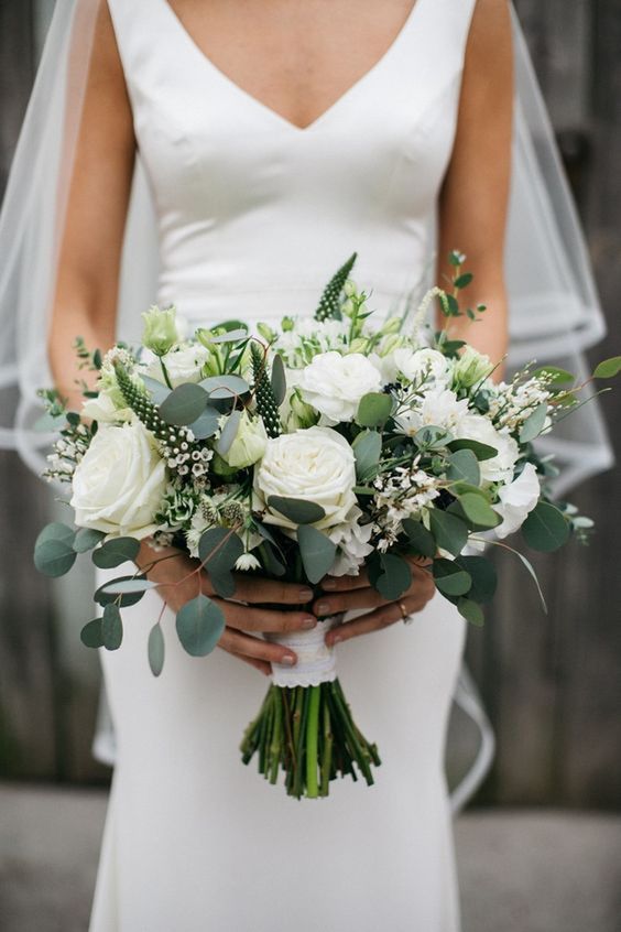 a white wedding bouquet of peony roses, astible, smaller white fillers and greenery is a chic idea for a summer bride
