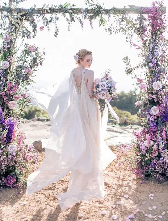 an airy and flowy blush wedding dress with a matching embellished shoulder cape veil are an amazing ensemble