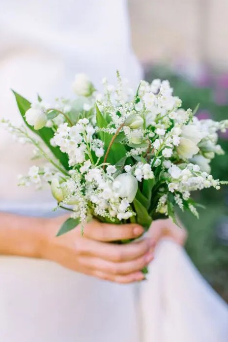 an all-white wedding bouquet of lily of the valley, snowdrops, greenery, tulips is a beautiful idea for a spring bride