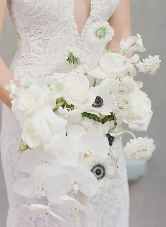 an all-white wedding bouquet of orchids, roses, anemones and some dahlias is a cool and fresh idea