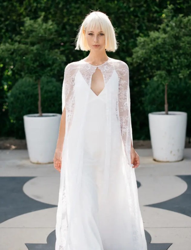 an ethereal lace cape looks amazing with a sleek minimalist spaghetti strap wedding gown and they a cool ensemble together