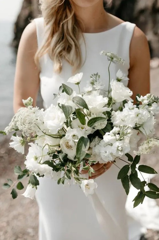 a beautiful all white wedding bouquet with lisianthus, campanula, lace flower, clematis, spirea, cosmos sister honey
