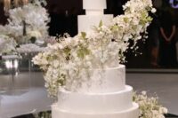 02 a beautiful formal white wedding cake with a large and lush white flower and green swirl around is a very exquisite idea