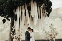 02 a beautiful outdoor wedding ceremony space with neutral streamers and pastel pink blooms forming a wedding altar
