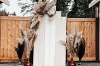 02 a boho western wedding backdrop with wooden slats, simple and black pampas grass in bottles and layered rugs