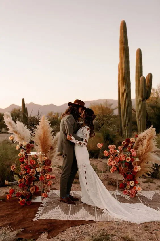 a catchy western wedding altar with super bright and bold roses, pampas grass, a woven rug and cacti in the backdrop